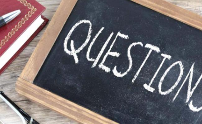 A small chalkboard withtheword "Questions" written on it in chalk.