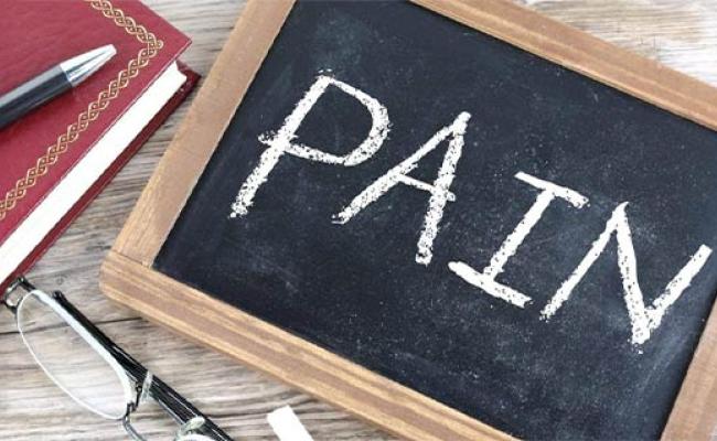 A chaalkboard laying flat on a table with the  word "PAIN" wrriten on it.