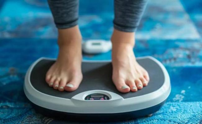Image focused on a floor scale with somebody standing on it.