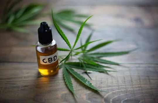 A bottle of CBD oil with a cannabis  leave beside it.