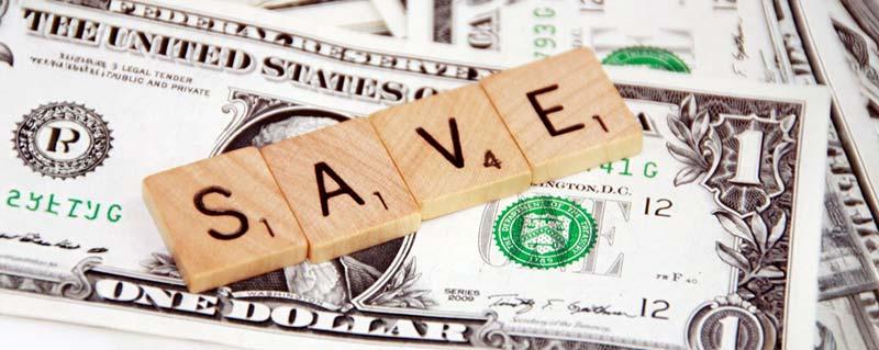 Wooden letters spelling SAVE on a pile of dollar bills